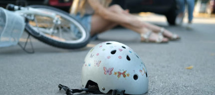 Capacete de ciclista caído no asfalto ao lado de bicicleta